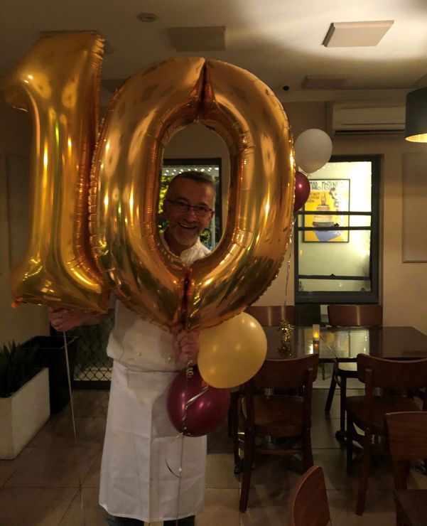 A man is holding balloons in the shape of the number 10