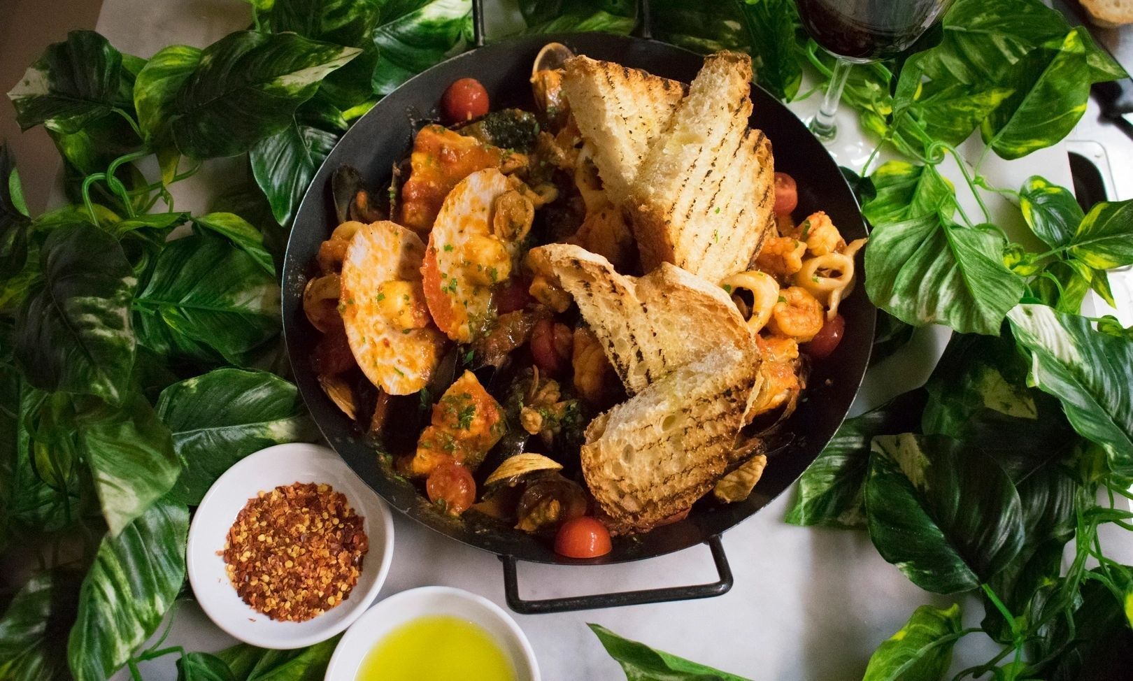 A pan filled with food and bread is sitting on a table.