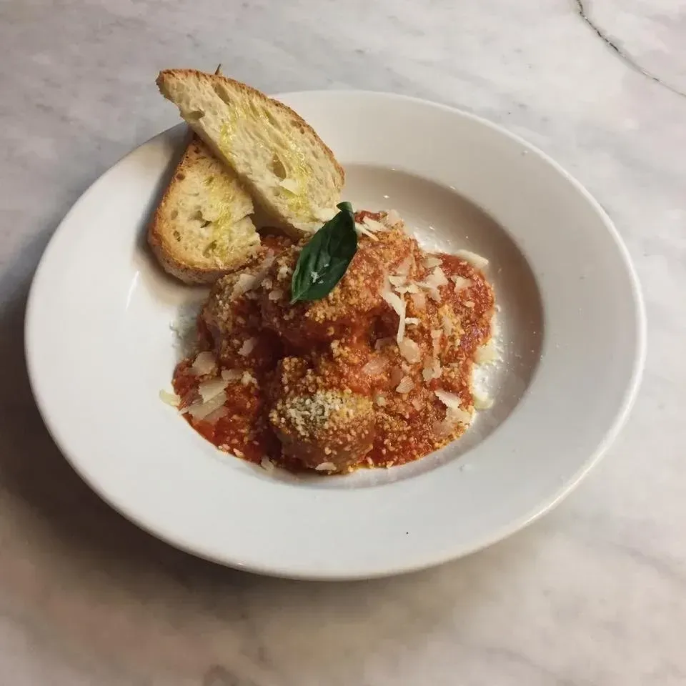 A white plate topped with meatballs and bread on a table