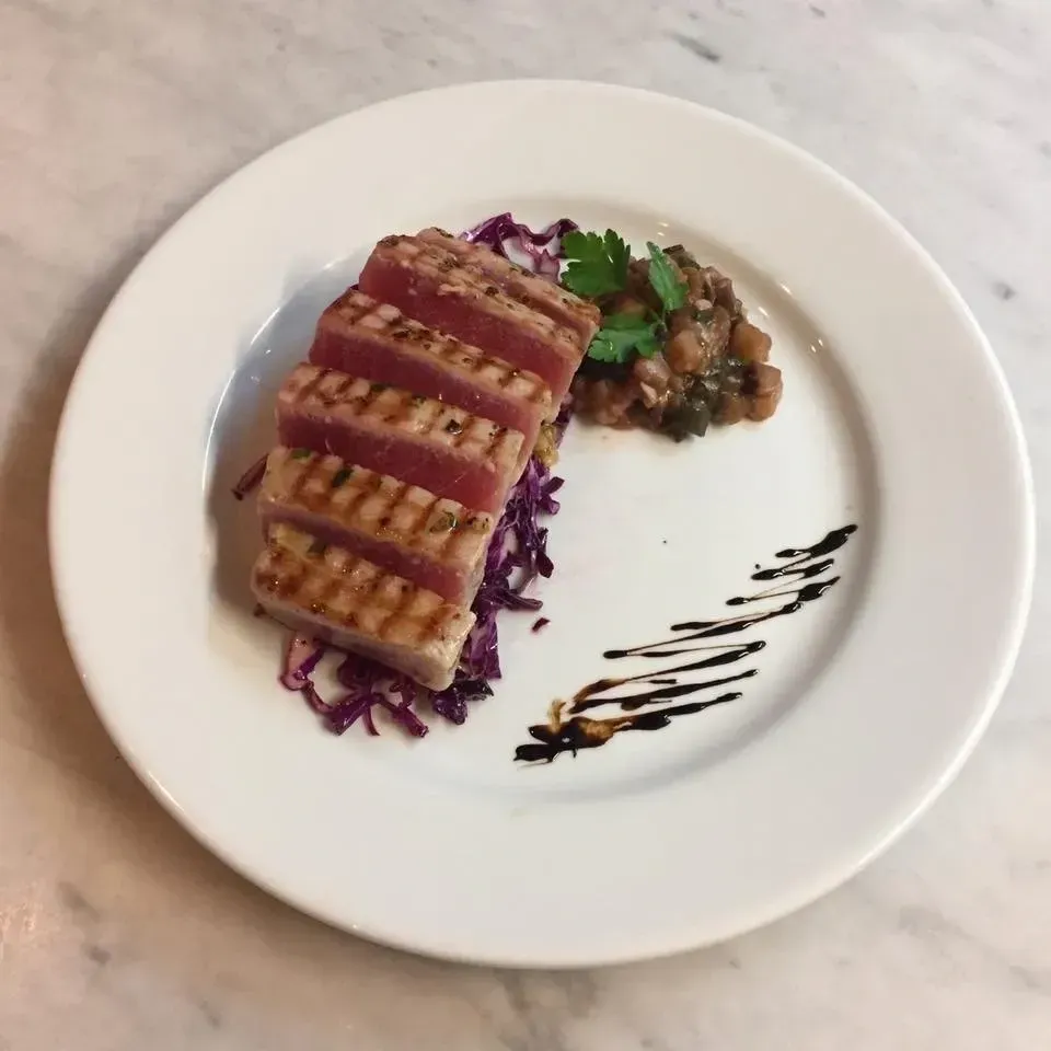 A white plate topped with meat and vegetables on a table
