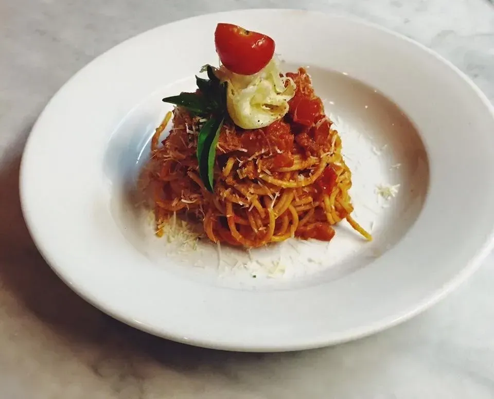 A white plate topped with spaghetti and tomatoes