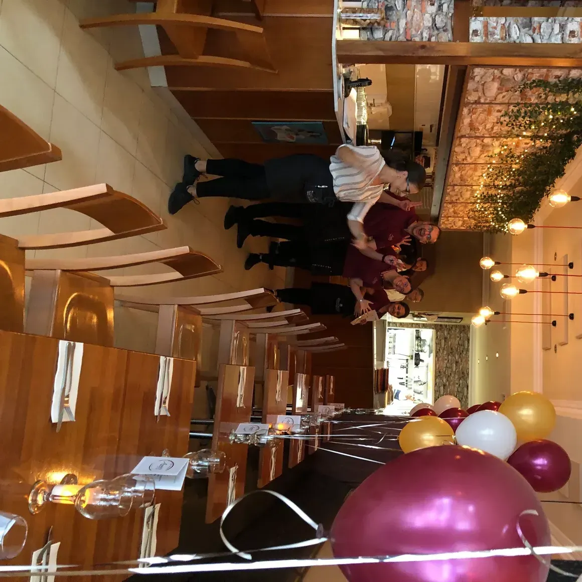 A group of people are standing in a restaurant surrounded by balloons