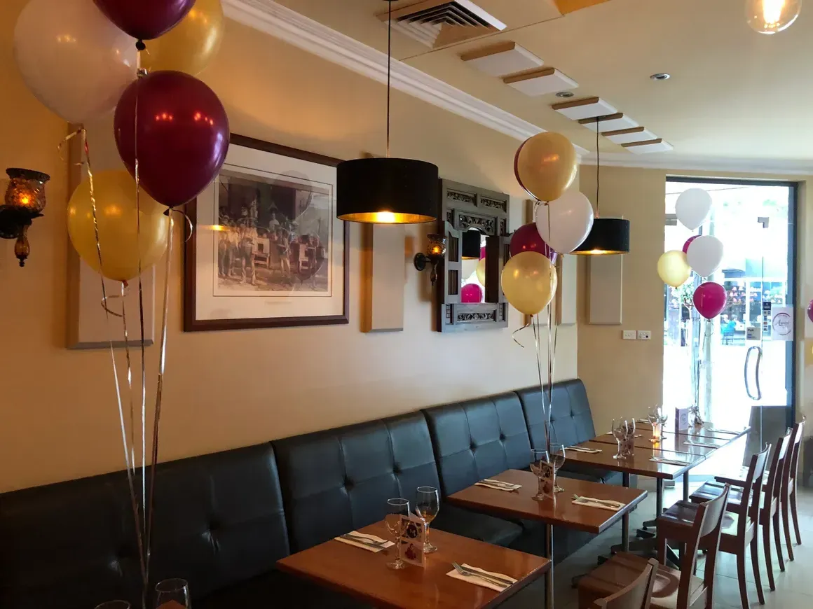 A restaurant with tables and chairs decorated with balloons