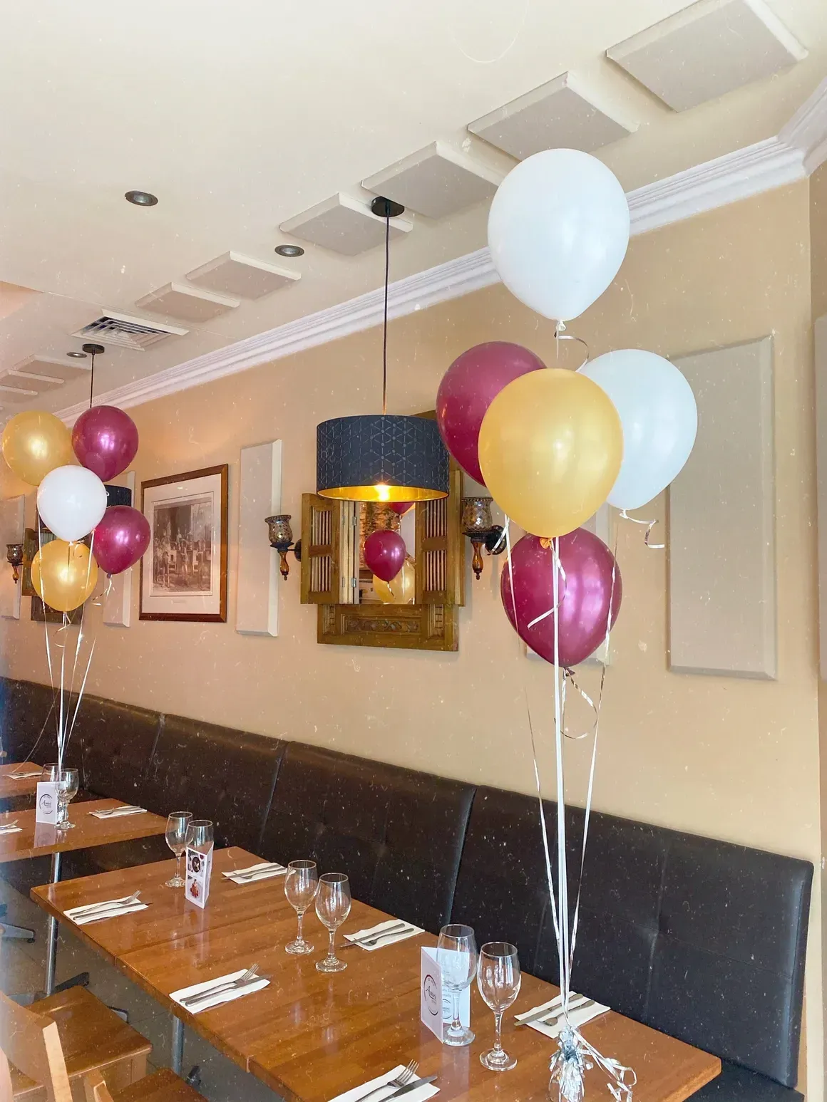 A restaurant with tables and balloons hanging from the ceiling