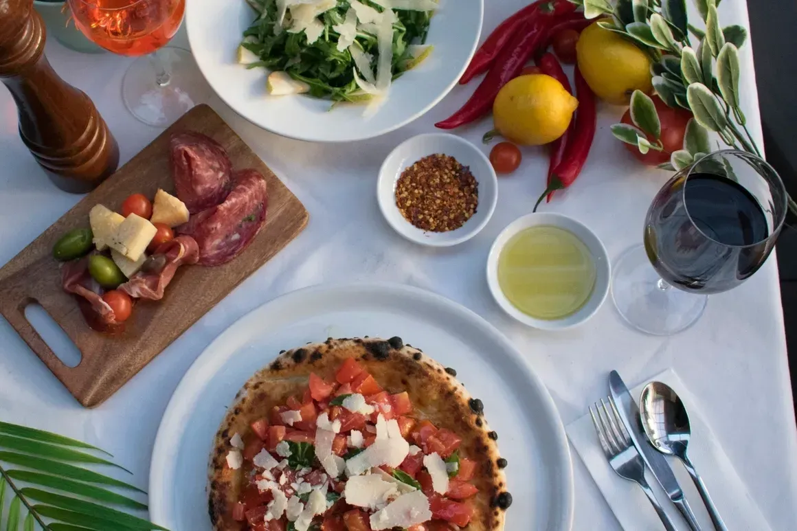 A table topped with plates of food and a glass of wine