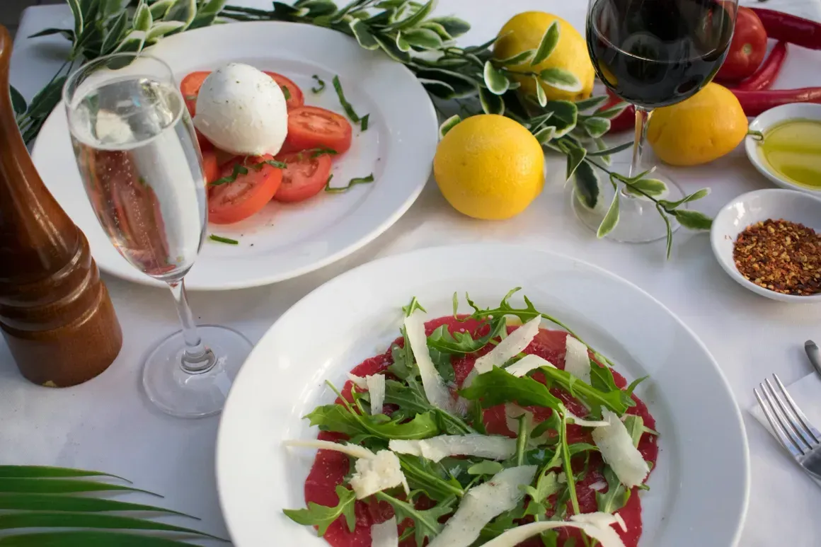 A table topped with plates of food and a glass of wine