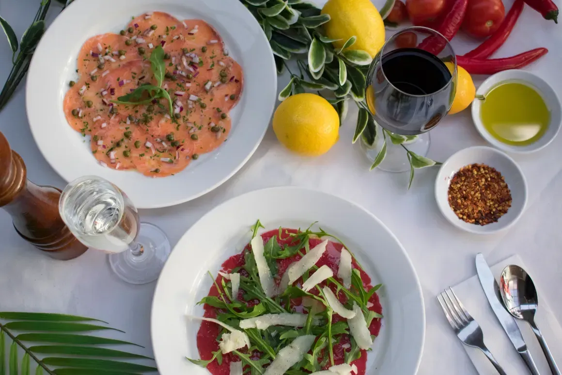 A table topped with plates of food and a glass of wine.