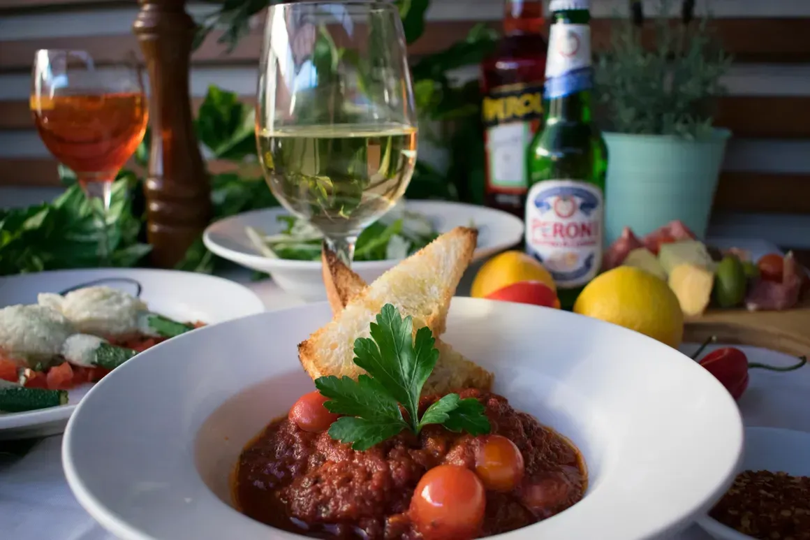 A bowl of food and a glass of wine on a table.