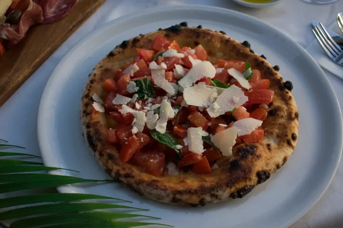 A pizza with tomatoes and cheese on a white plate