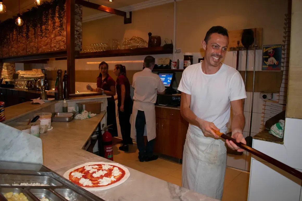 A man is making a pizza in a restaurant.
