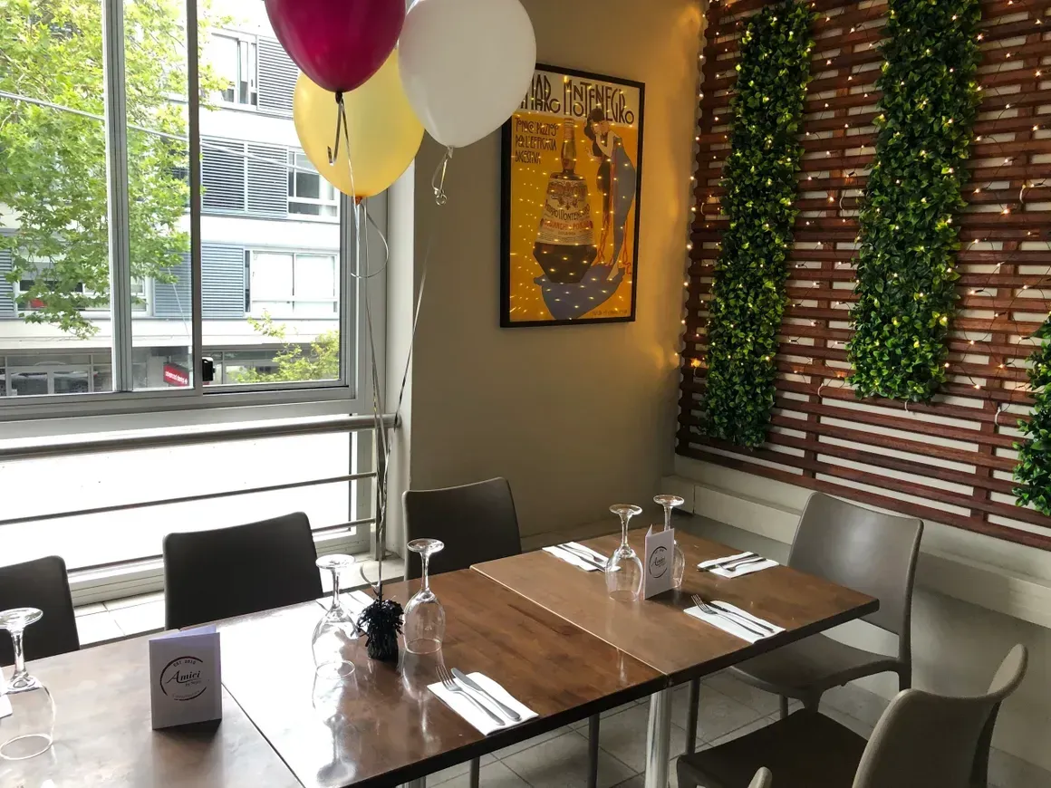 A restaurant with a table and chairs and balloons hanging from the ceiling.