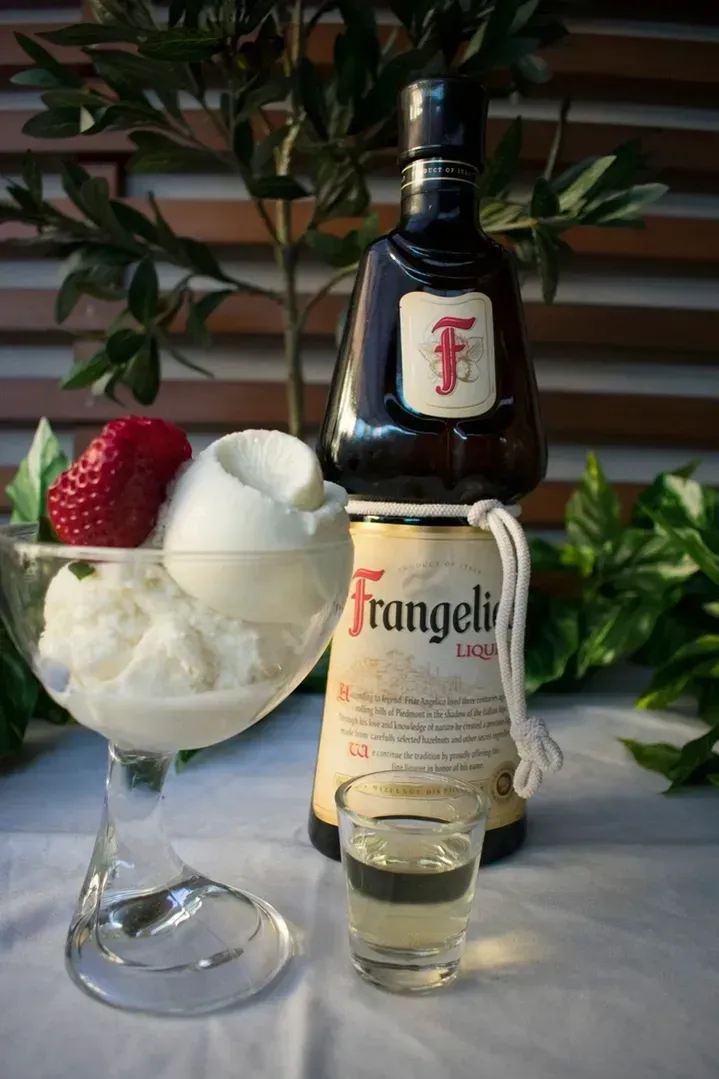 A bottle of frangelic next to a glass of ice cream