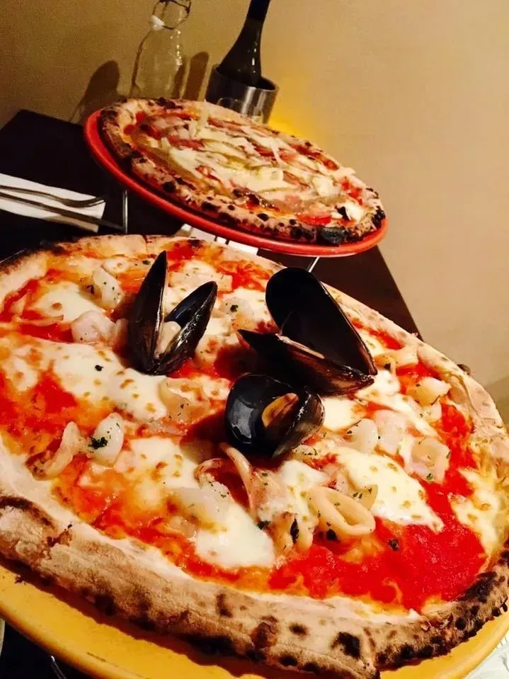 Two pizzas are sitting on a yellow plate on a table