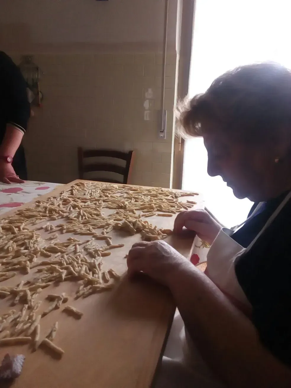 A woman sits at a table with noodles on it
