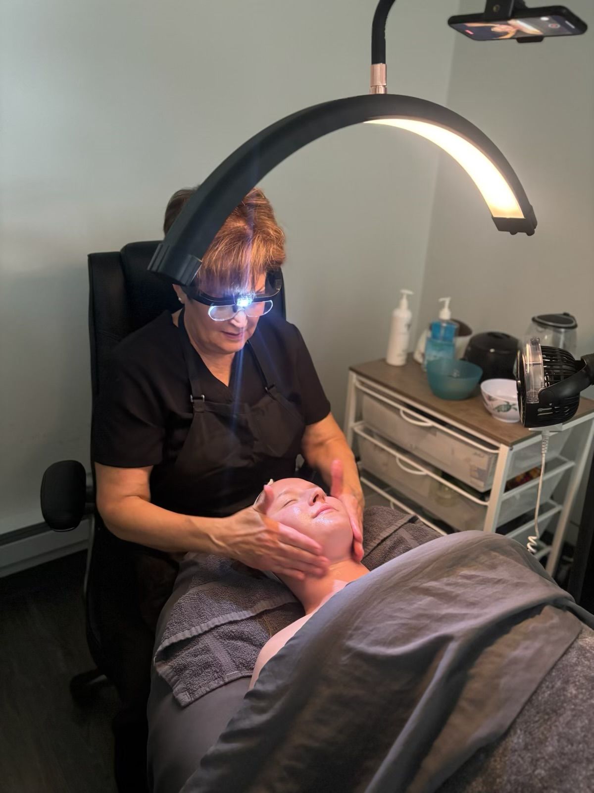 A woman wearing glasses is giving a man a massage