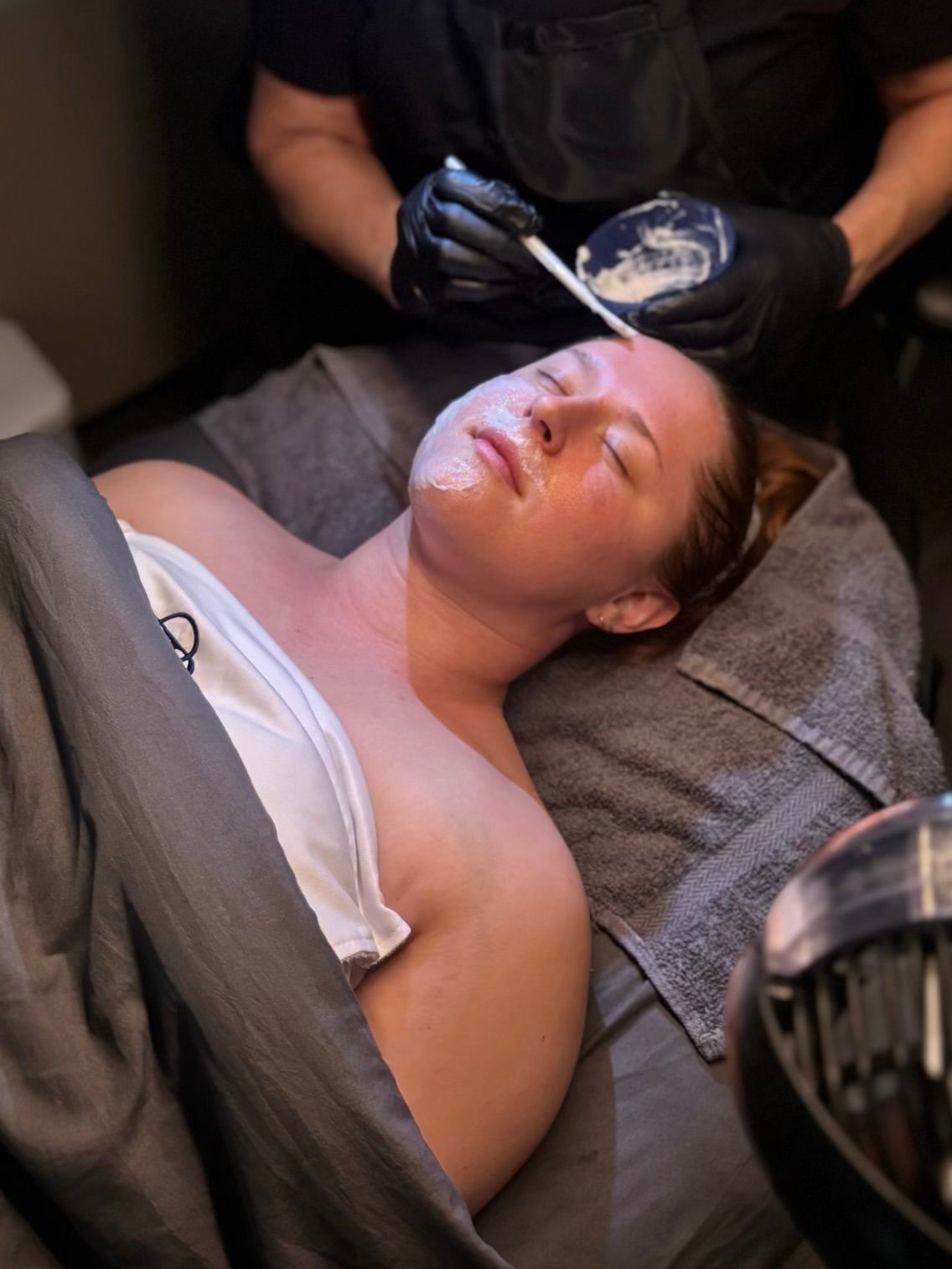 A woman is getting a facial treatment at a spa