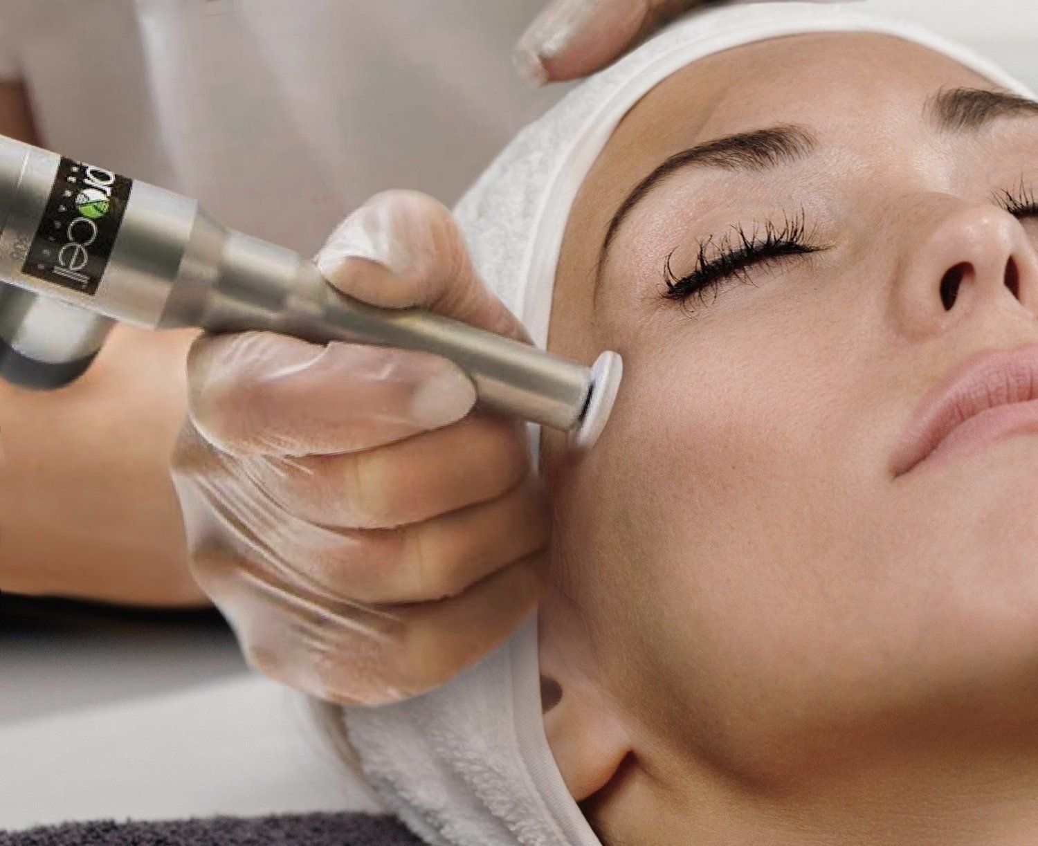 A woman with her eyes closed is getting a treatment on her face