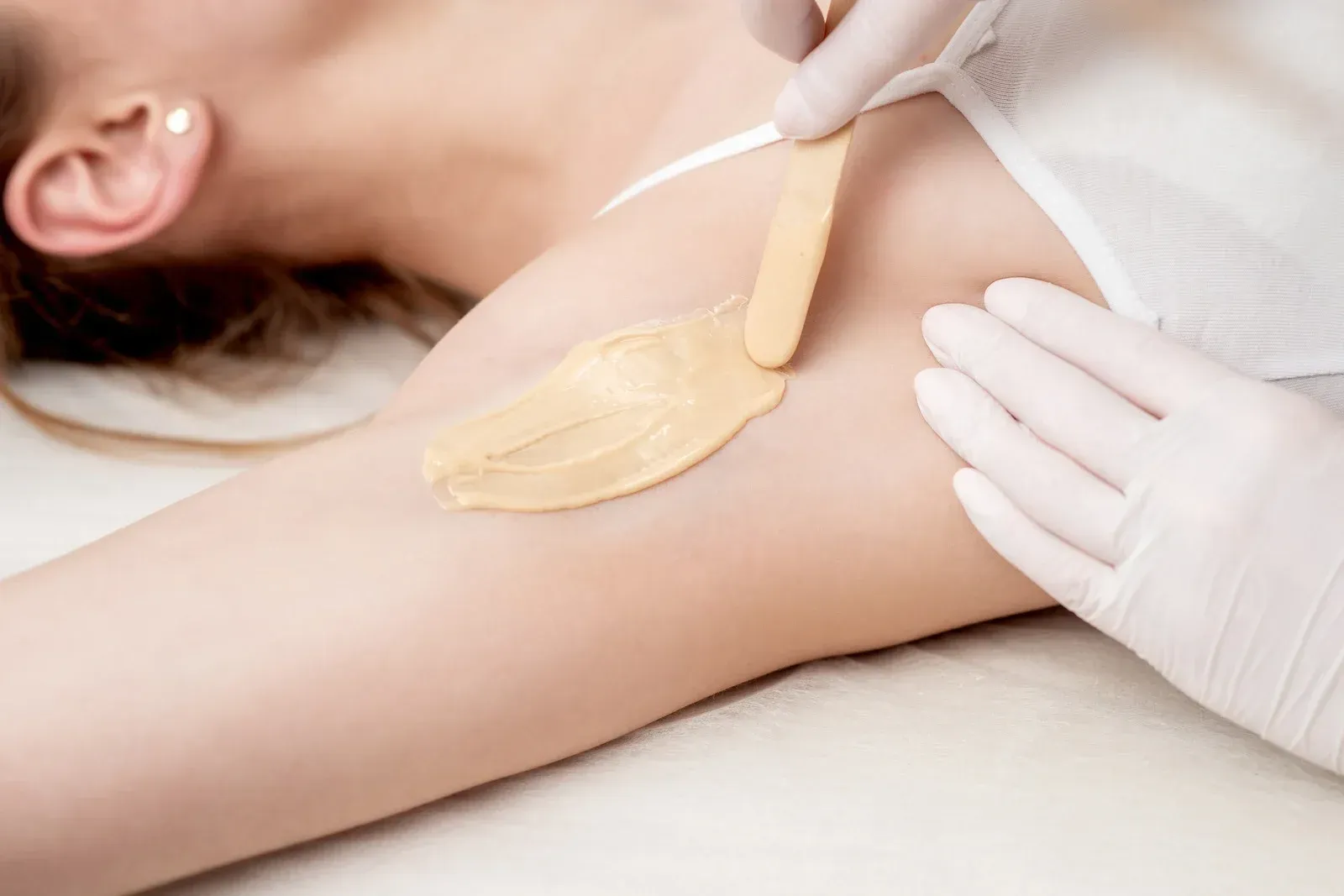 A woman is getting her armpit waxed in a beauty salon.
