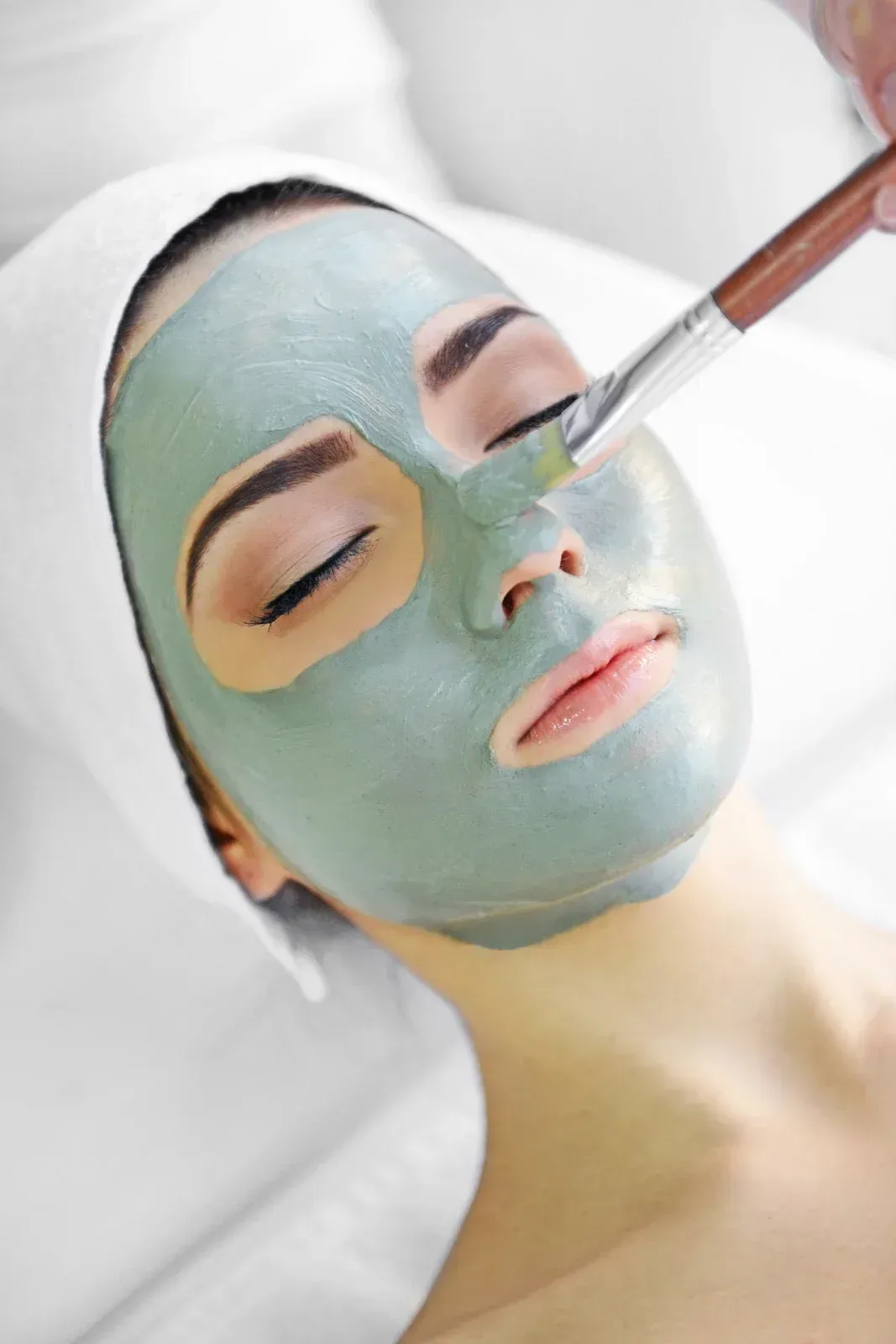 A woman is getting a facial mask on her face