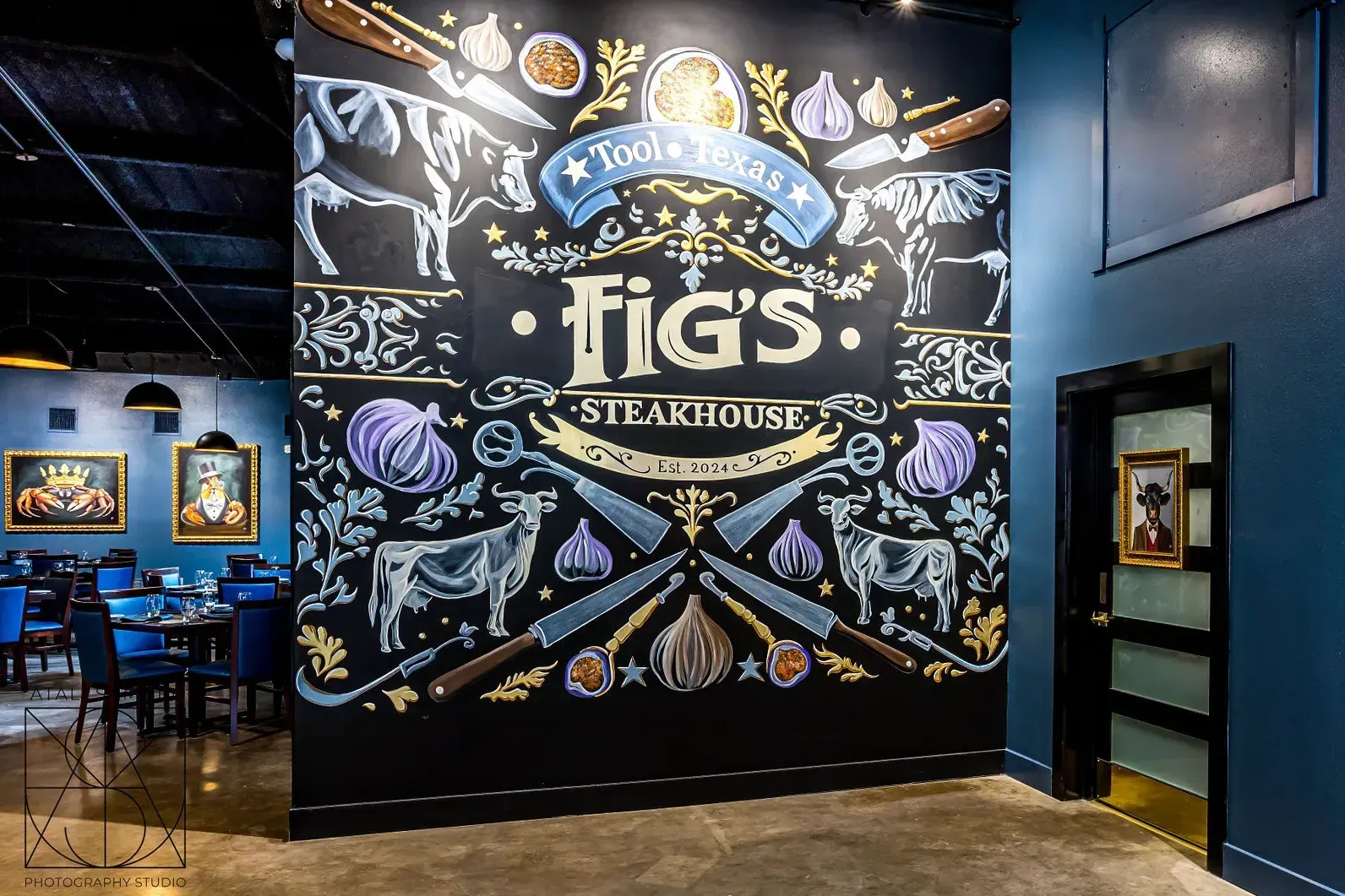 Fig's Steakhouse interior with large chalkboard mural featuring cows, onions, and crossed knives. Blue wall, dining area.