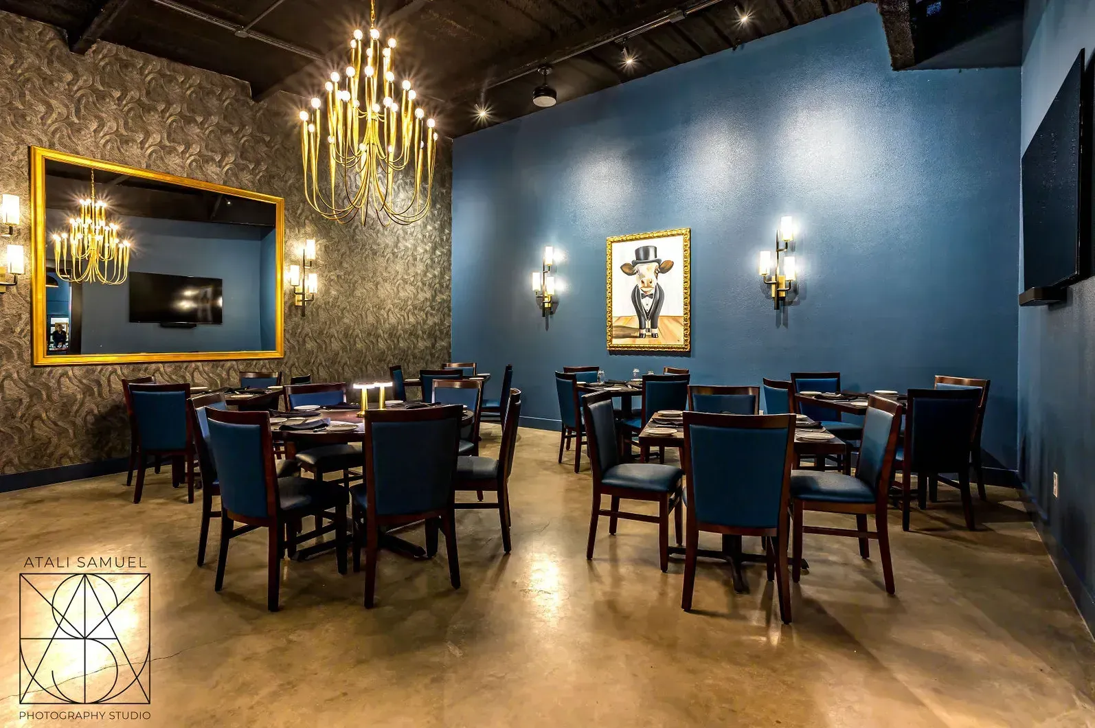 A dining room with blue walls, dark furniture, and a gold chandelier.