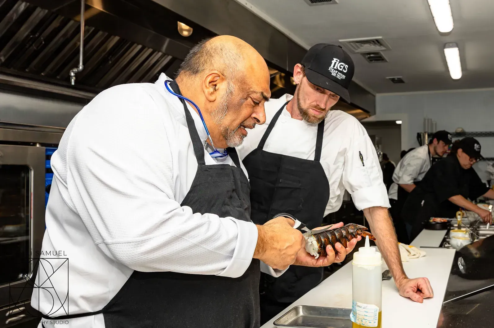 Chef examining food with another chef in a professional kitchen.