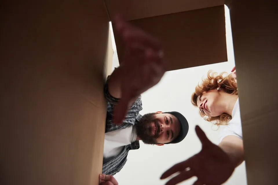 a couple looking down into a cardboard box being opened