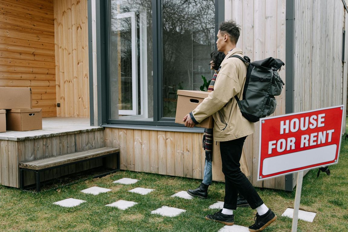 a man carrying a cardboard box with a backpack, walking away from a 