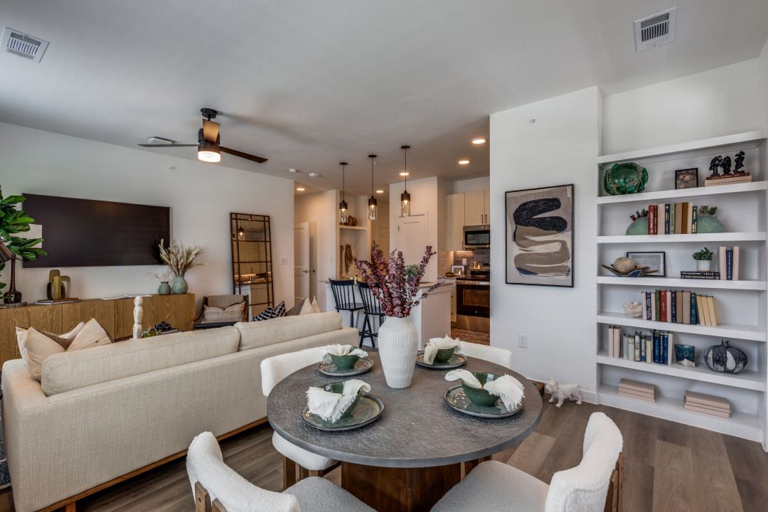 A living room with a round table and chairs and a ceiling fan.