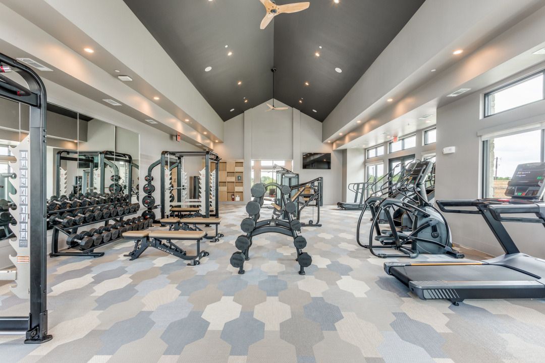 A large gym with a lot of equipment and a ceiling fan.