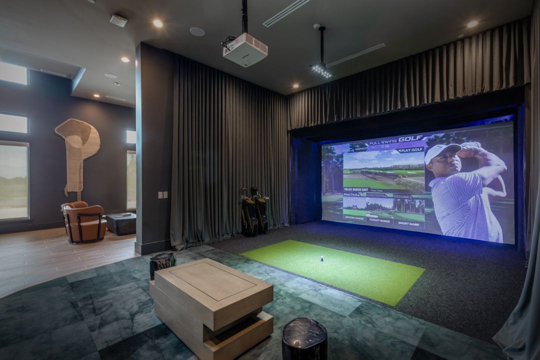 A living room with a projector screen and a golf simulator.