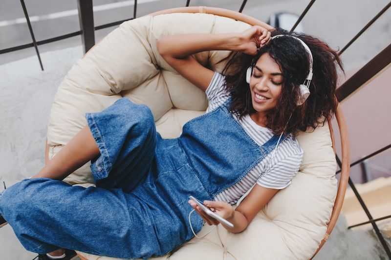 A woman is sitting in a chair listening to music on her phone.