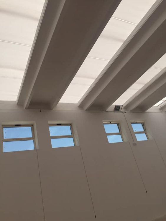 Operaio edile con in mano progetti e casco, sovrapposto a edifici cittadini e a un cantiere.