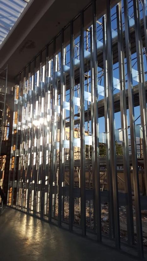 Stanza in costruzione; griglia di barre d'armatura esposta sulle pareti, pavimento di macerie, scala e assi di legno.