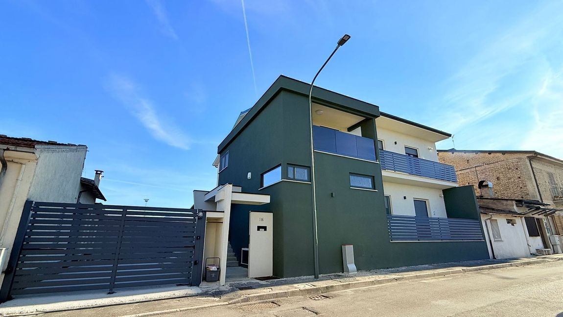 Moderni palazzi residenziali con facciata in mattoni e balconi in vetro contro il cielo azzurro.