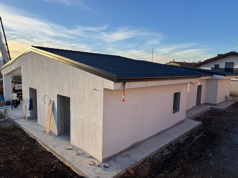 Pannelli solari installati su un tetto di tegole, cielo azzurro, montagne sullo sfondo.
