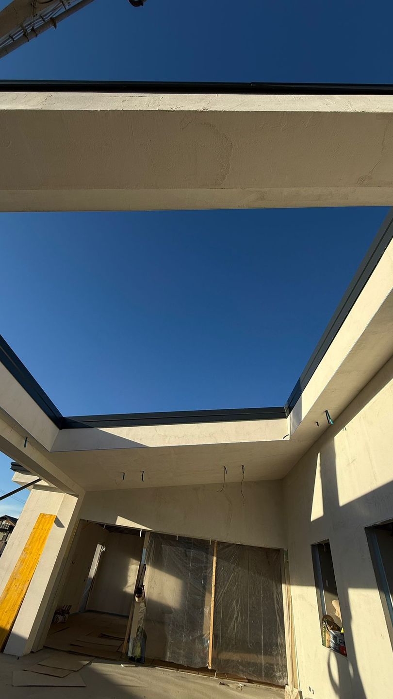 Casa beige a due piani con scala esterna, ringhiere in ferro battuto nero e un piccolo portico.