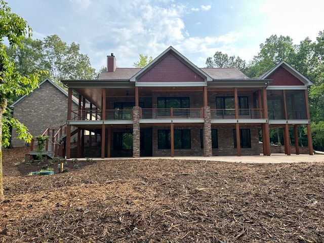 A large house with a lot of windows is sitting on top of a dirt field.