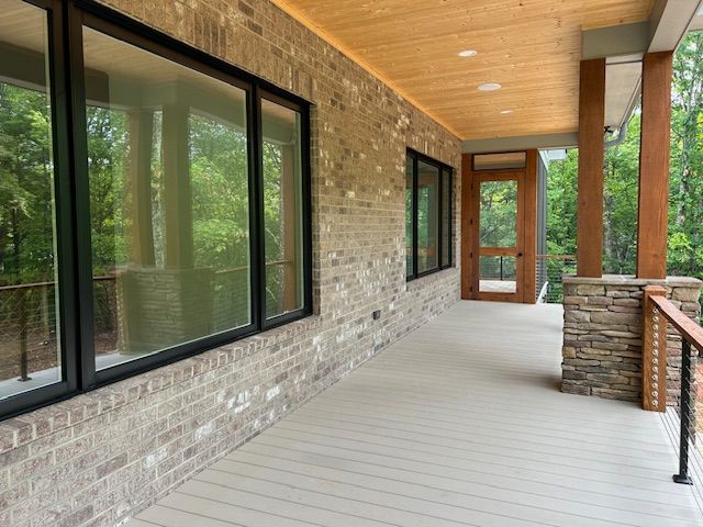 A large porch with a brick wall and lots of windows.
