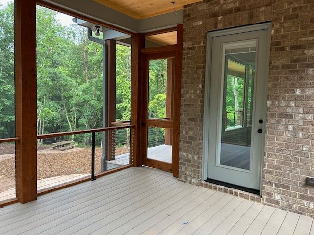 A screened in porch with a brick wall and a door.