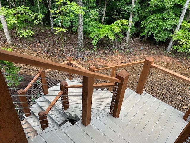 A wooden deck with stairs leading up to a forest.