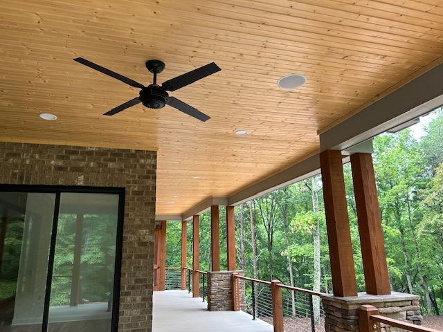 A ceiling fan is hanging from the ceiling of a porch.
