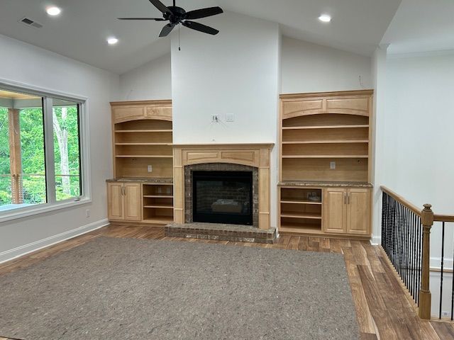 A living room with a fireplace , shelves , and a ceiling fan.