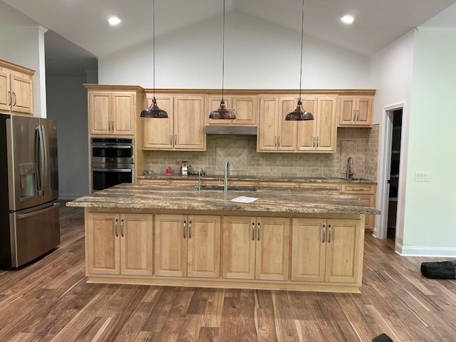 A kitchen with wooden cabinets , granite counter tops , and a large island.