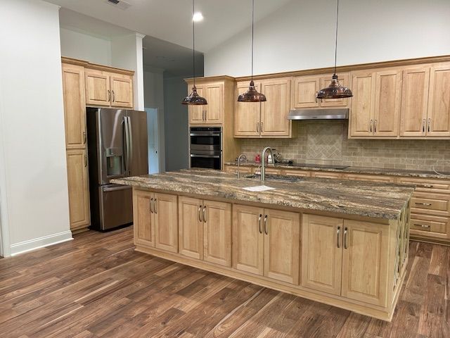 A kitchen with wooden cabinets , granite counter tops , stainless steel appliances and a large island.