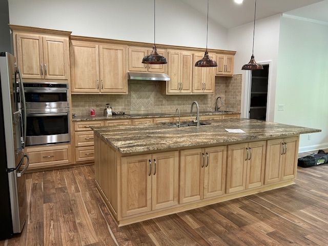 A kitchen with wooden cabinets , granite counter tops , and stainless steel appliances.