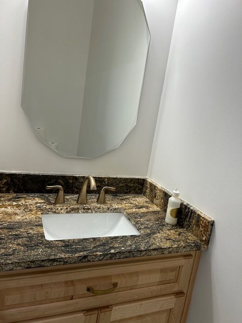 A bathroom with a sink , mirror and soap dispenser.