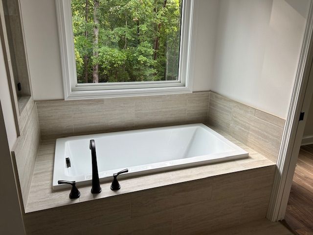 A bathtub in a bathroom next to a window.