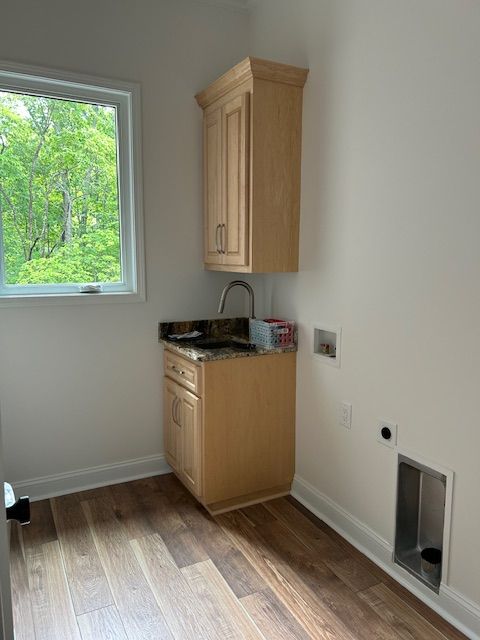 A laundry room with wooden cabinets , a sink , and a window.
