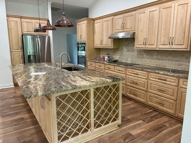 A kitchen with wooden cabinets , granite counter tops , stainless steel appliances and a large island.